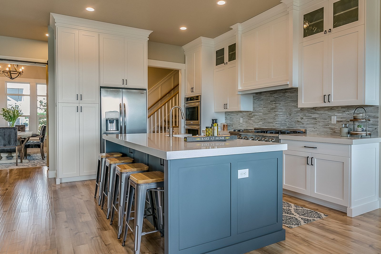 Traditional kitchen design by Axiom Renovation in the Bay Area with white and cabinets, blue island, a farmhouse sink, and elegant lighting fixtures.