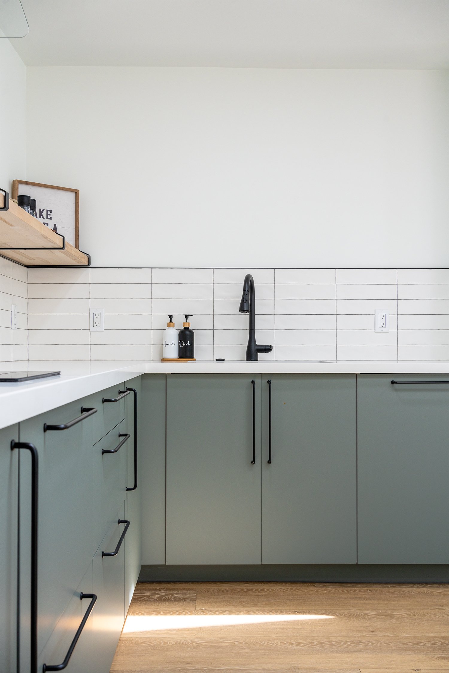 Modern kitchen green cabinetry design by Axiom Renovation featuring sleek gray cabinets, minimalist handles, and a clean tile backsplash.