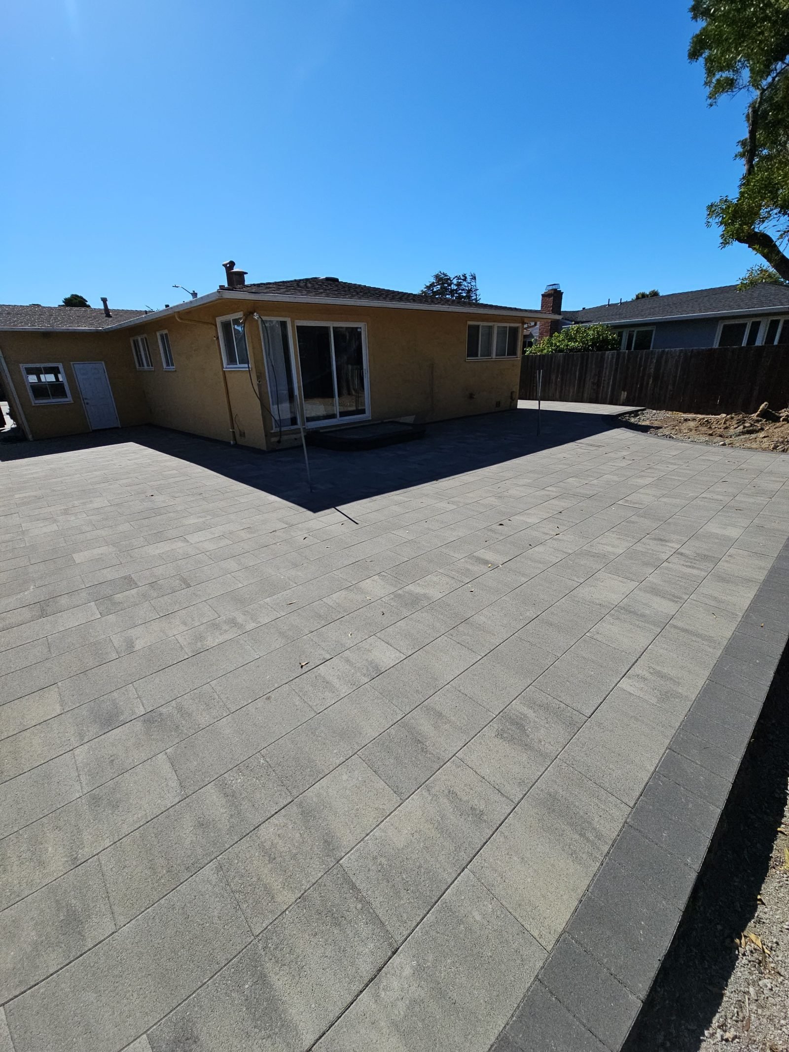 Backyard paver patio with a charcoal border course