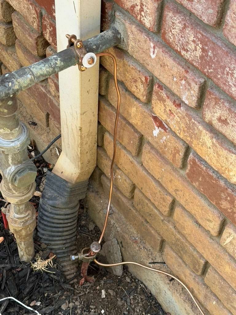 Downspout connected to an underground drain line at the base of a wall