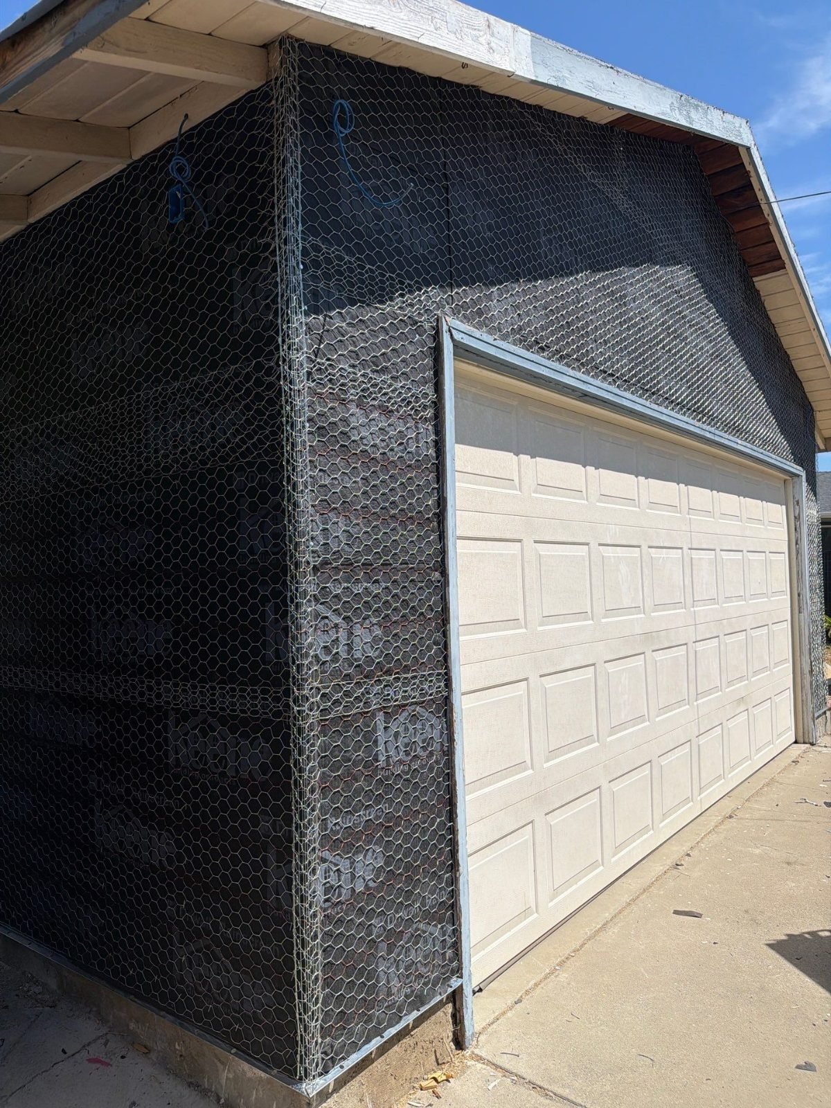 Garage exterior wrapped in weather barrier and wire lath before a new stucco coat