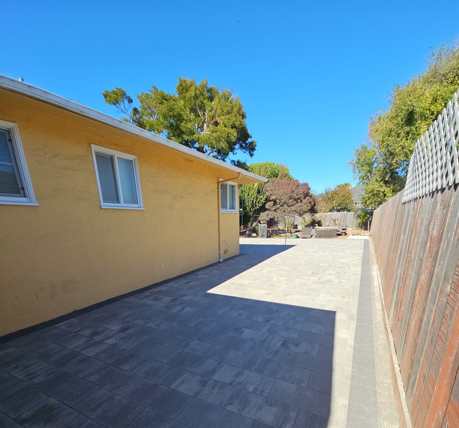 Side yard paved with large-format concrete pavers
