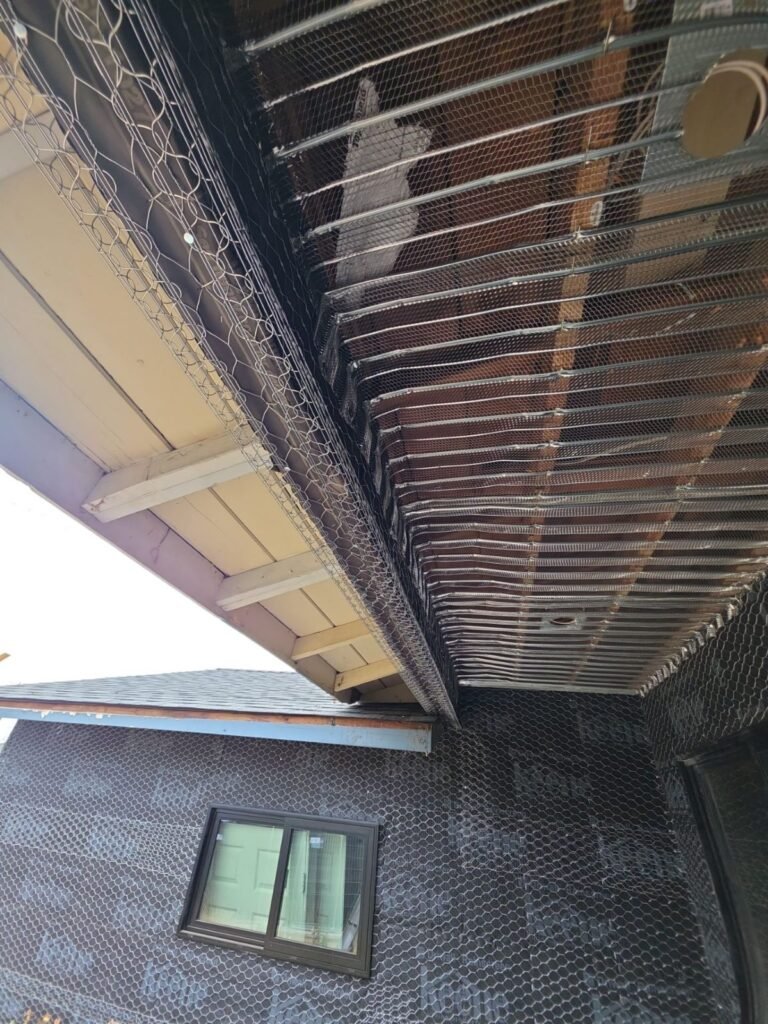 Wire lath over weather-resistive paper on a second-story wall and eave above an asphalt shingle roof