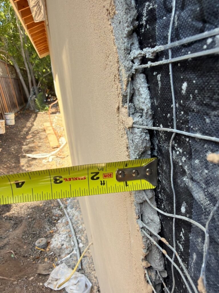 Tape measure checking stucco thickness over wire lath and building paper